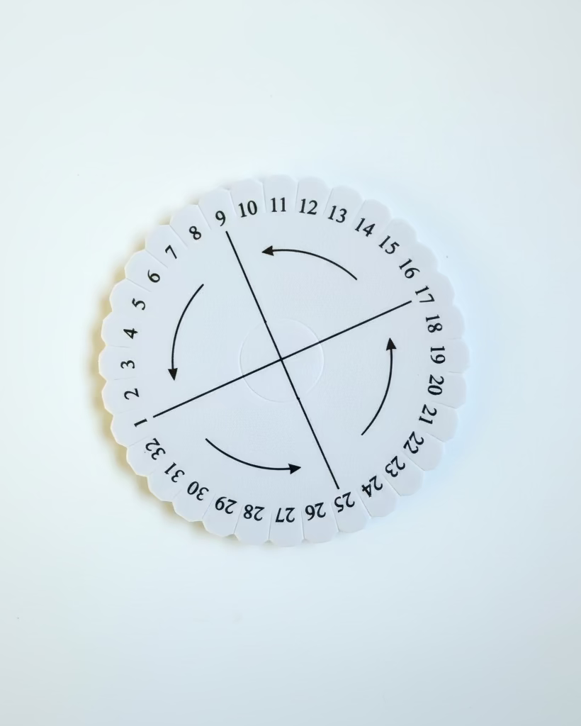 A circular white paper spinner with black printed numbers 1 through 36 and directional arrows, sealed in a clear plastic bag on a white background.